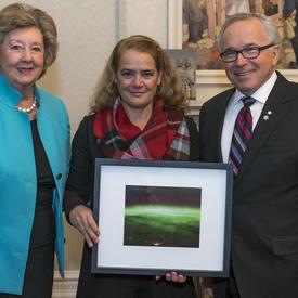 The Governor General holding a photo taken from space, stands in between Their Honours the Honourable Janice C. Filmon, Lieutenant Governor of Manitoba, and the Honourable Gary Albert Filmon