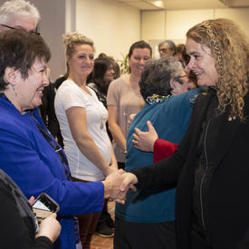 The Governor General, Julie Payette, meets people in a crowd.  She is seen shaking the hand of a woman. 