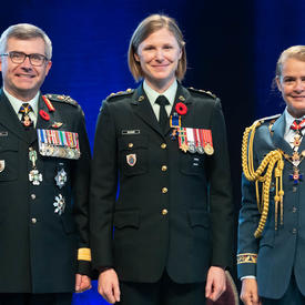 Recipient Lieutenant-Colonel Claire Katherine Bramma stands between the Vice Chief of the Defence Staff,   Lieutenant-General Paul Wynnyk (on the left) and Her Excellency the Right Honourable Julie Payette (on the right).