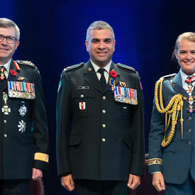  Recipient Major Trevor Jain stands between the Vice Chief of the Defence Staff, Lieutenant-General Paul Wynnyk (on   the left) and Her Excellency the Right Honourable Julie Payette (on the right). 