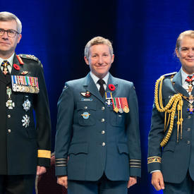 Recipient Major Jennifer Lynn Morrison stands between the Vice Chief of the Defence Staff, Lieutenant-General Paul   Wynnyk (on the left) and Her Excellency the Right Honourable Julie Payette (on the right).