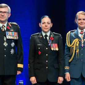 Recipient Sergeant Roxane St. Michael stands between the Vice Chief of the Defence Staff, Lieutenant-General Paul   Wynnyk (on the left) and Her Excellency the Right Honourable Julie Payette (on the right).