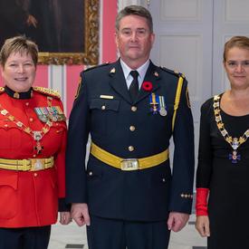 La gouverneure générale et le commissaire de la GRC prennent une photo avec un récipiendaire de l'Ordre du mérite des corps policiers.