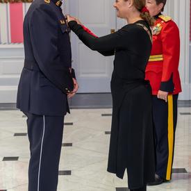 La gouverneure générale épingle une médaille sur la poitrine d'un récipiendaire de l'Ordre du mérite des corps policiers.