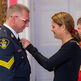 The Governor General pins a medal on the chest of a recipient of the Order of Merit of the Police Forces.