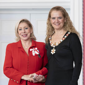 Patsy Gallant serre la main de la gouverneure générale.  Ils sourient à la caméra et portent toutes les deux l'insigne de l'Ordre du Canada.