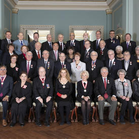 Une photo de groupe des 40 récipiendaires de l'Ordre du Canada en compagnie de la gouverneure générale. Les récipiendaires sont organisés en 4 rangées, la première assise, les 3 suivantes sont debout.