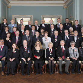 A group photo of the 40 recipients of the Order of Canada along with the Governor General. The recipients are organised in 4 rows, the first seated, the following 3 are standing. 