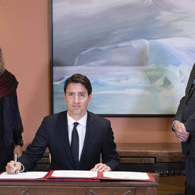 Le premier ministre signe le livre des serments. Le gouverneur général et le greffier du Conseil privé à ses côtés. 