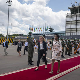 La gouverneure générale marche sur un tapis rouge en direction vers l'avion. 