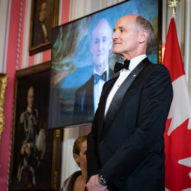 Colm Feore stands on stage to receive his award. 