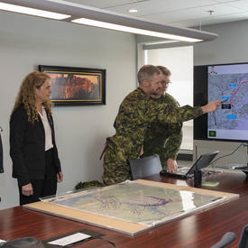La gouverneure générale voit une carte des inondations sur un écran de télévision. 