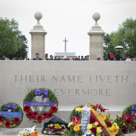 Des fleurs sont déposées devant un monument au Cimetière de guerre canadien de Bény-sur-Mer.