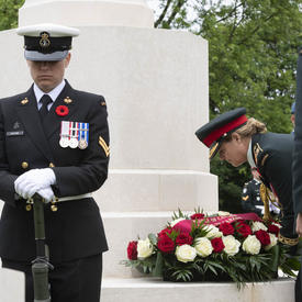 Governor General Julie Payette is laying a wreath at the foot of a white monument.