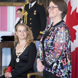 Claudine Roy se tient à l'avant de la salle avec la gouverneure générale.