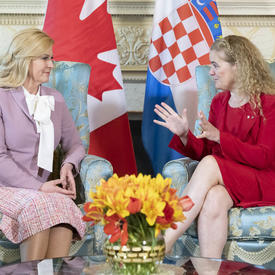 The President of the Republic of Croatia and the Governor General are sitting in chairs speaking to each other. 