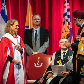The Governor General stands to receive a Doctor of Laws honoris causa. The Honourable Harjit S. Sajjan, Minister of National Defence stands beside her. 