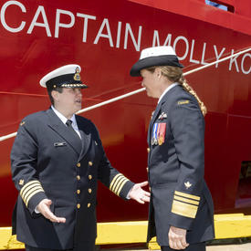 La Capitaine Catherine Lacombe, commandante du NGCC Captain Molly Kool, serre la main de la gouverneure générale Julie Payette devant le navire Captain Molly Kool. Les deux femmes portent l'uniforme de la Garde côtière canadienne.