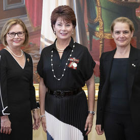 Une grande rousse se tient entre Judy May Foote, lieutenante-gouverneure de Terre-Neuve-et-Labrador, et la gouverneure générale Julie Payette.