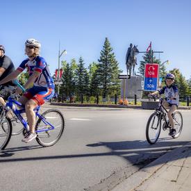 A family cycles by the Queen Elizabeth II statue on Sussex Drive