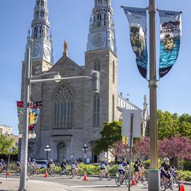 Participants cycle past the Notre-Dame Cathedral Basilica on Sussex Drive
