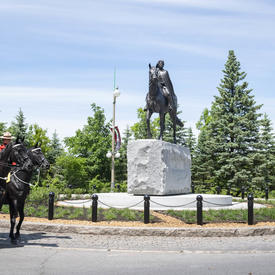 The horses from the RCMP Musical Ride are standing beside the Queen Elizabeth II Equestrian Monument.