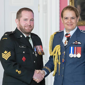 Le caporal-chef Archer serre la main de la gouverneure générale après avoir reçu sa médaille.