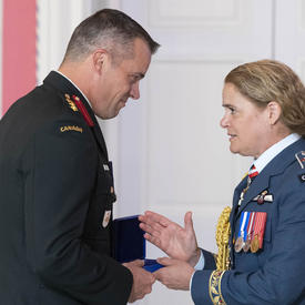 Le colonel Huet accepte sa médaille et serre la main de la gouverneure générale.