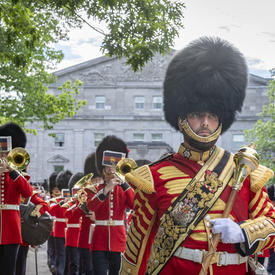 The Band of the Ceremonial Guard marches away from the Rideau Hall entrance while providing musical support.