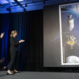 The Governor General claps on stage as the Apollo 11 stamps are unveiled. 