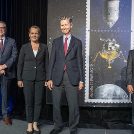 La gouverneure générale pose pour une photo sur scène parmi les cadres supérieurs à côté des timbres Apollo 11.