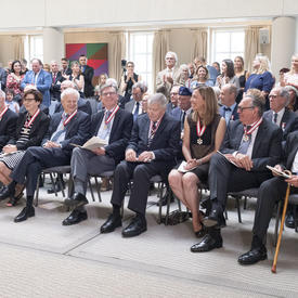 Les invités présents applaudissent et félicitent les membres nouvellement investis de l'Ordre du Canada.