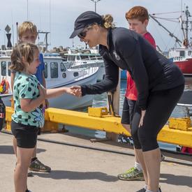 The Governor General meets and shakes hands with a young girl in the port of Île d’Entrée.