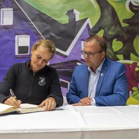 The Governor General sits with His Worship Jonathan Lapierre at a reception and signs the municipality's guest book.
