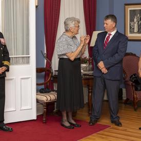 (Left to Right) a photo of an officer, Her Honour the Honourable Antoinette Perry, the Honourable Dennis King, and Her Excellency the Right Honourable Julie Payette, inside Government House.