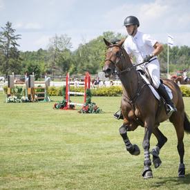 Front view of a rider and his mount turning to the right in an outdoor course during a competition.
