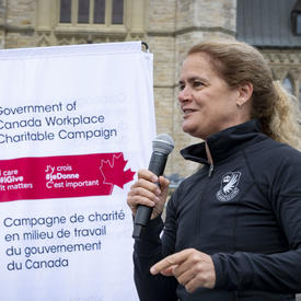 The Governor General holding a microphone addressing the crowd.