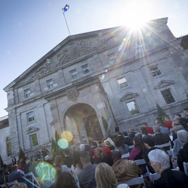 A photo of the front entrance of Rideau Hall, with guests seated for a ceremony.