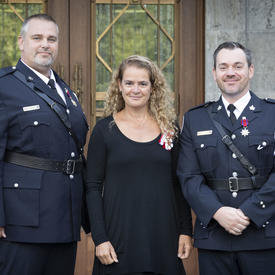 The Governor General stands between two Medal of Bravery recipients for a photo.