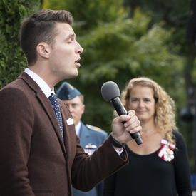 The National Anthem is sung by a vocalist, as the Governor General watches on in solidarity.