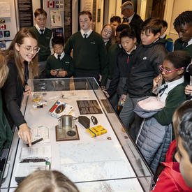 Students are shown elements from the Dare to Dream exhibit by an employee of the Office of the Secretary to the Governor General.