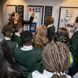 Students are shown elements from the Dare to Dream exhibit by an employee of the Office of the Secretary to the Governor General.
