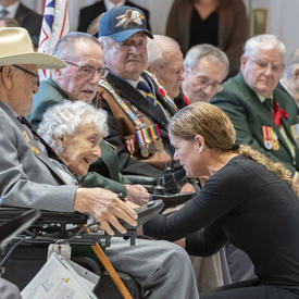 The Governor General kneels down and speaks with a veteran during the launch of the 2019 National Poppy Campaign.