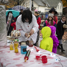 Kids look on as a staff member creates a Halloween food creation.