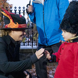 The Govenror General greets a young child dressed as a member of the Royal Canadian Mounted Police.