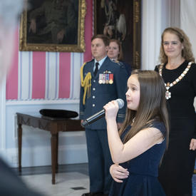 The National Anthem is sung by a young lady at the Order of Canada ceremony.