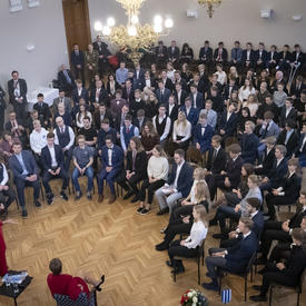 Wide-view of a room full of people who are seated, listening to the Governor General.