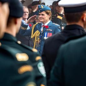 Governer General Julie Payette, wearing the Royal Canadian Air Force uniform, is saluting troops..