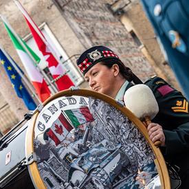 A member of the Canadian Armed Forces Pipes and Drums Band holds a brass drum.