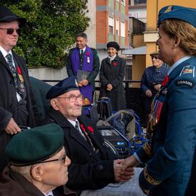Governor General Julie Payette, wearing the Royal Canadian Air Force uniform, is mingling outside with veterans.